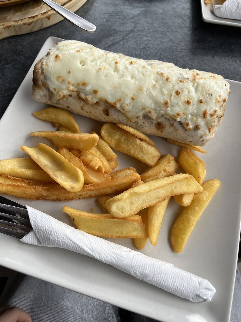 Durum gratinado relleno de carne y verduras, acompañado de patatas fritas